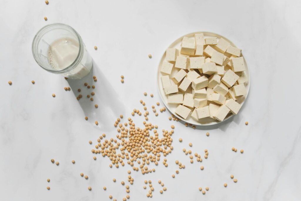 Top view of tofu cubes, soybeans, and soy milk on a white background – perfect for vegan food themes.